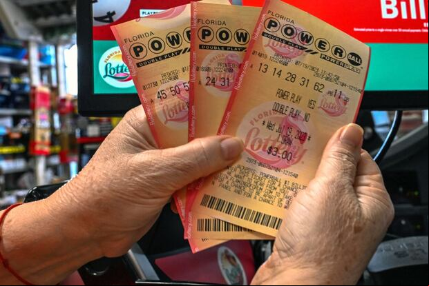 Una mujer sostiene boletos de lotería Powerball dentro de una tienda en Homestead, Florida, el 19 de julio de 2023 (Foto: Giorgio Viera / AFP)