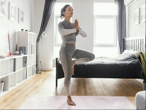 En esta imagen se aprecia a una mujer muy concentrada mientras realiza un ejercicio en casa. (Foto: Freepik)